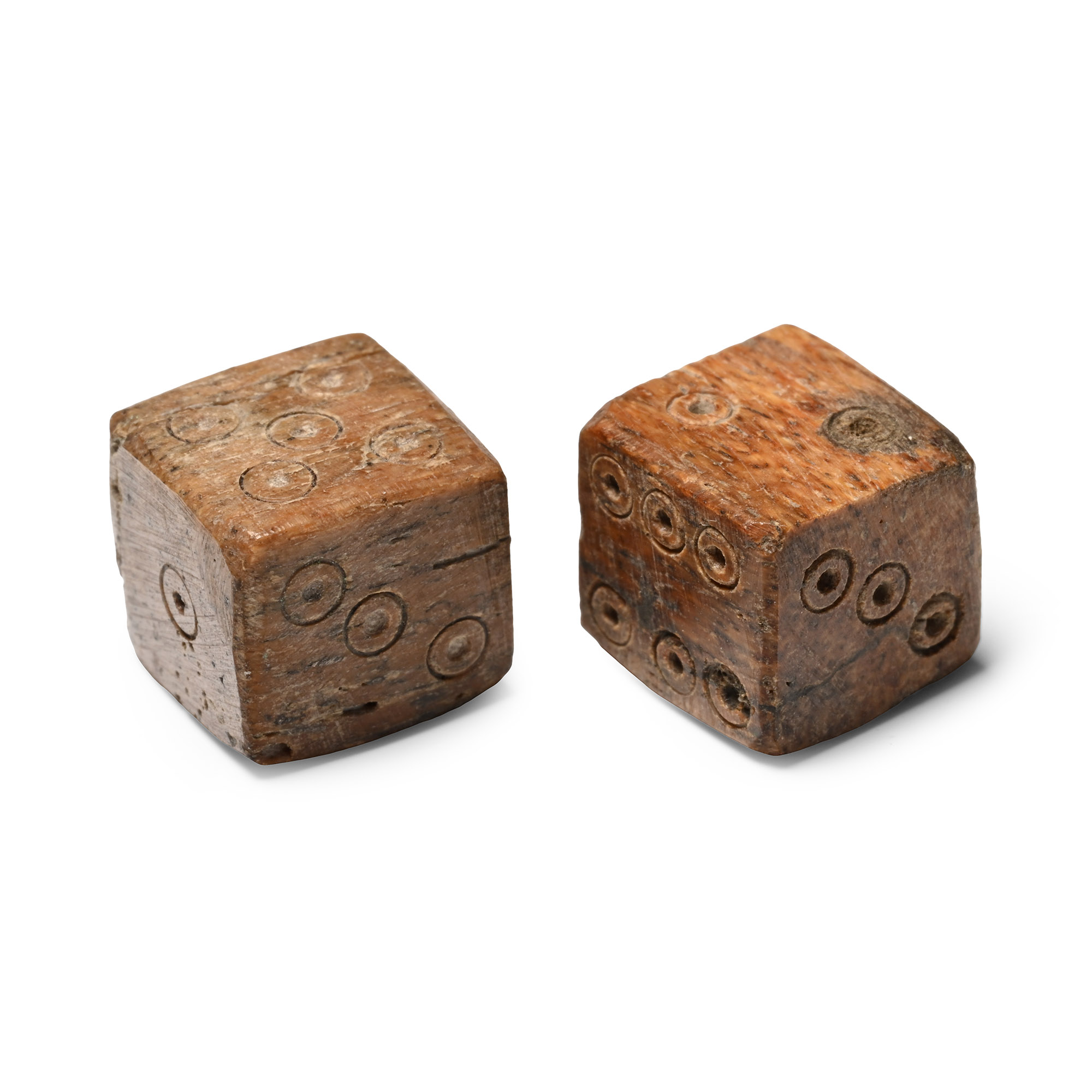 A pair of Roman bone dice with ring-and-dot pips, opposite faces summing to seven