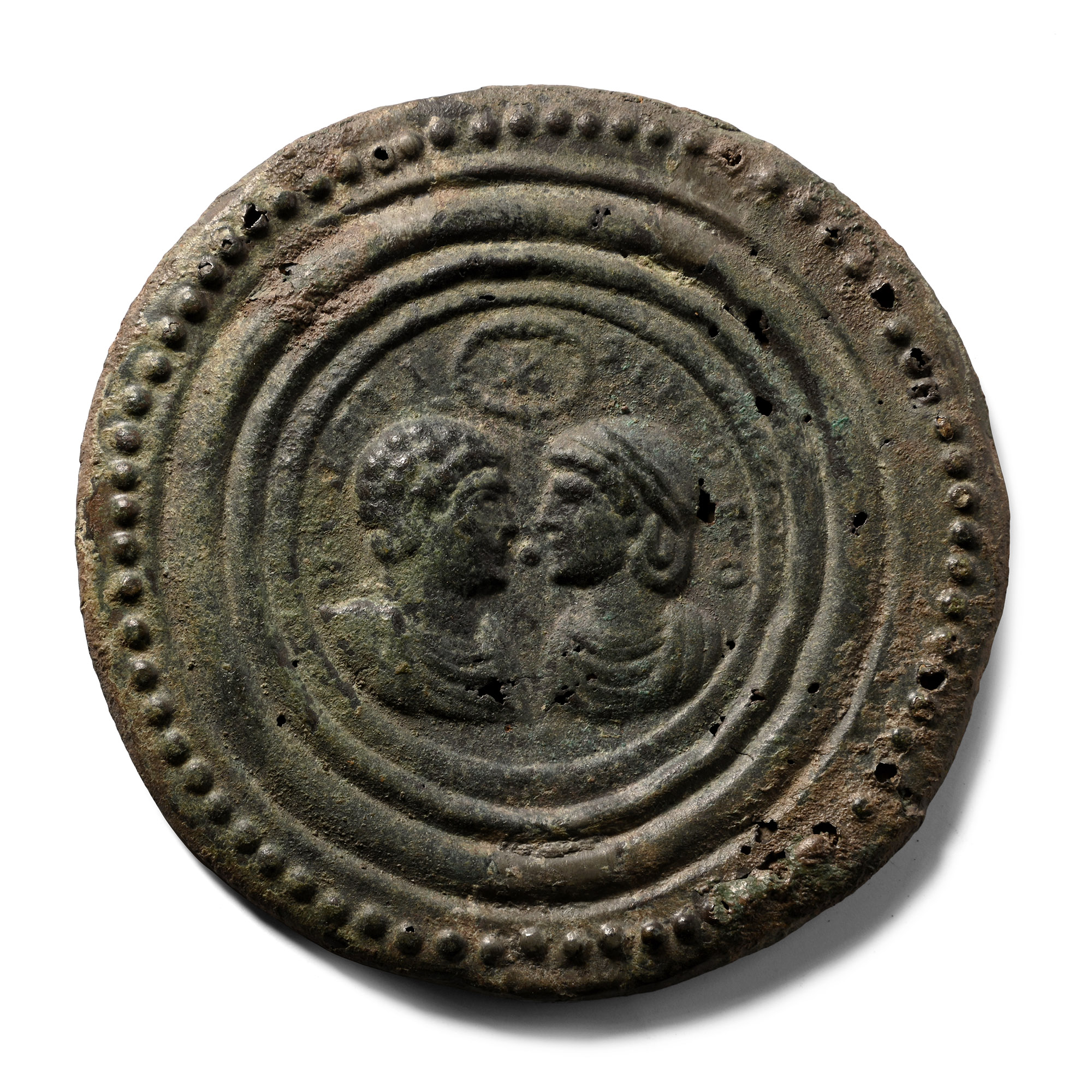A Roman bronze disc with two confronting draped busts at its centre within a beaded rim