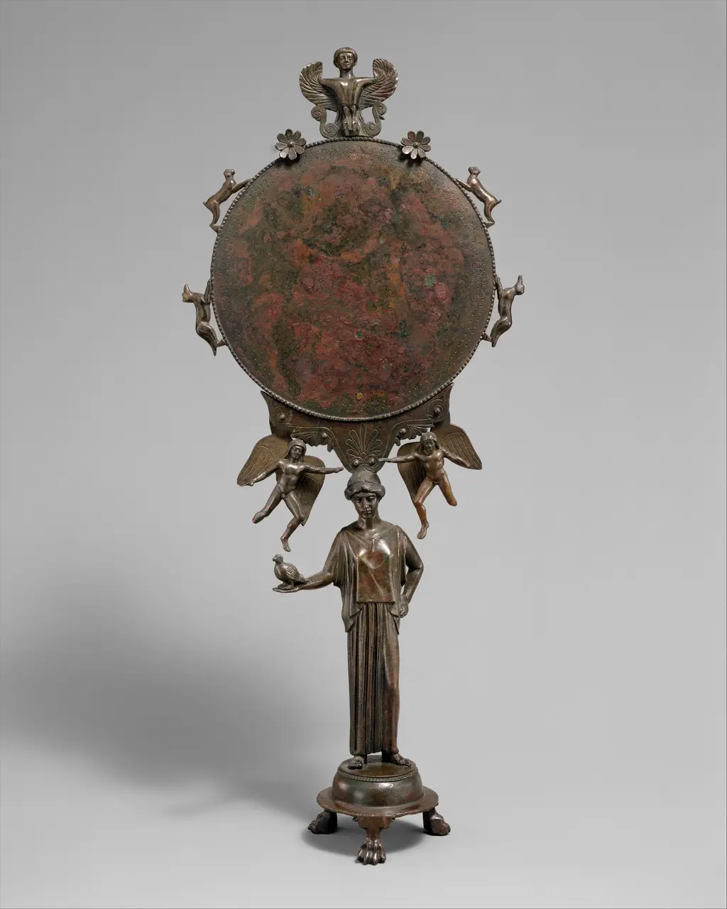 A Greek caryatid mirror, a bronze disc held aloft by a standing female figure