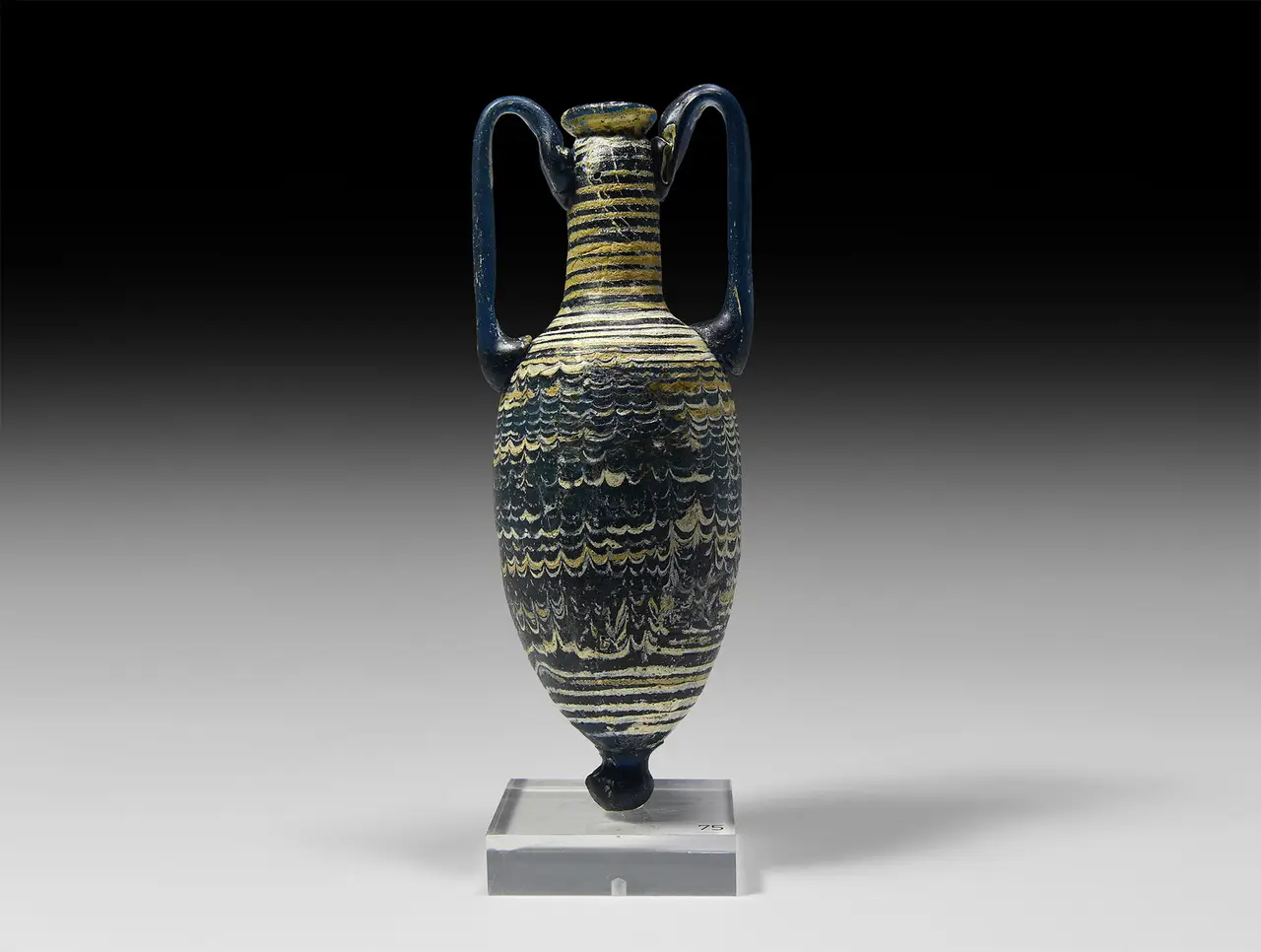 A Hellenistic core-formed glass amphoriskos, the dark body trailed with combed yellow and white waves