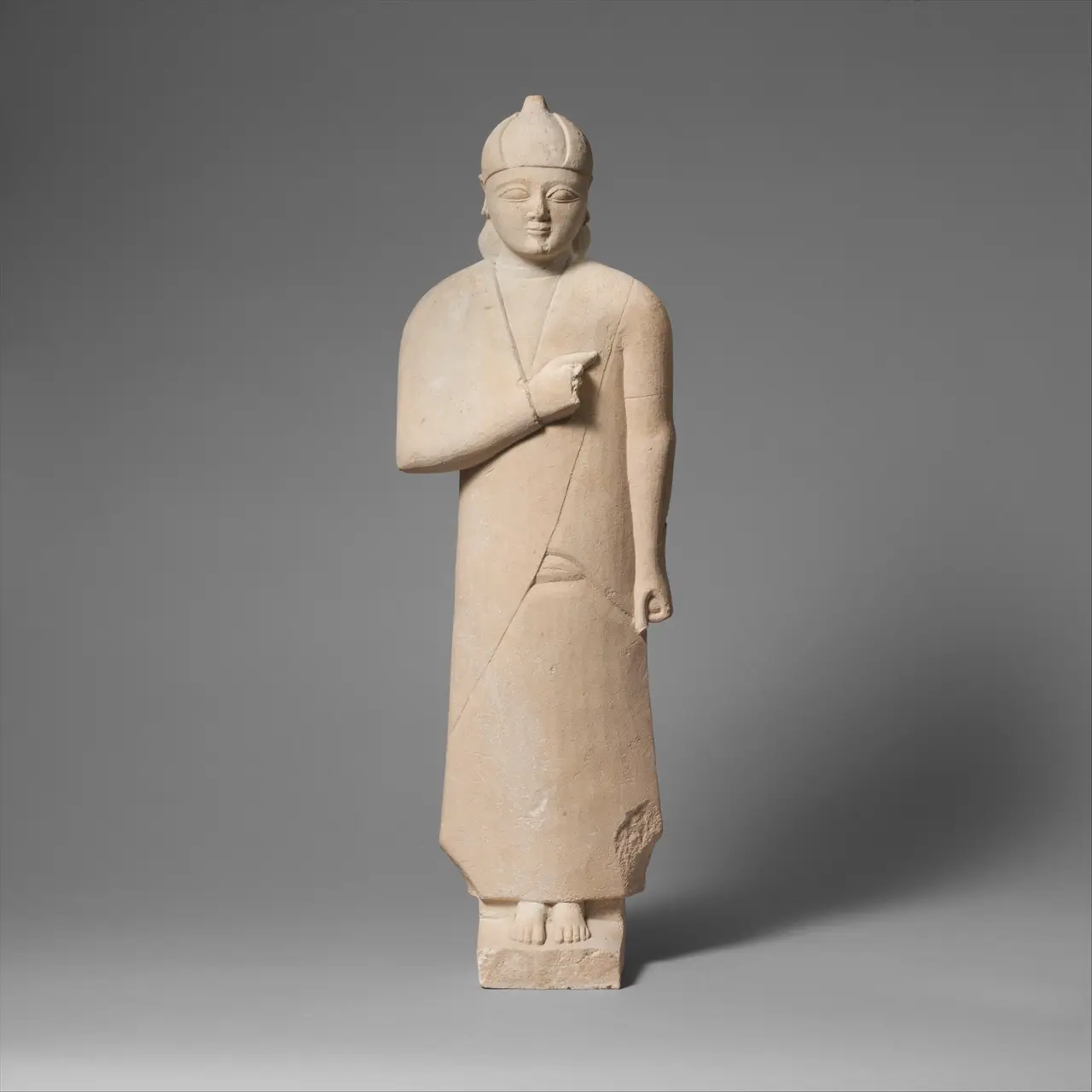 A complete Cypriot limestone votary statuette in a long robe and pointed cap