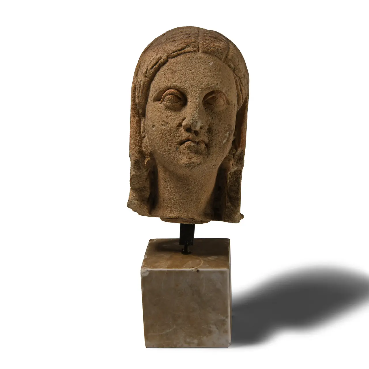 A Cypriot limestone head of a goddess, her hair dressed in radiating segments