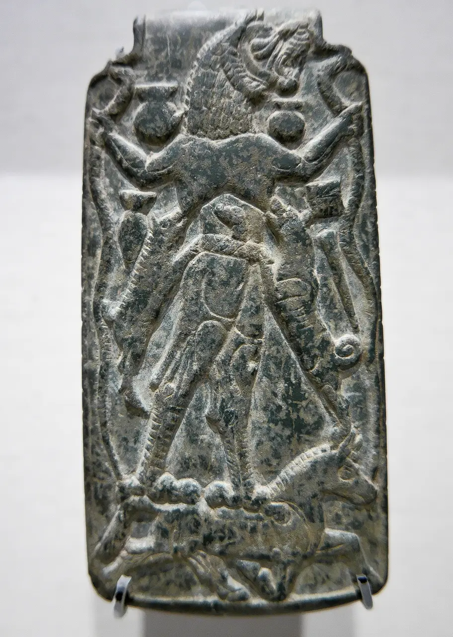 Stone amulet of the demon Lamashtu standing on a donkey, suckling a dog and a pig, gripping serpents