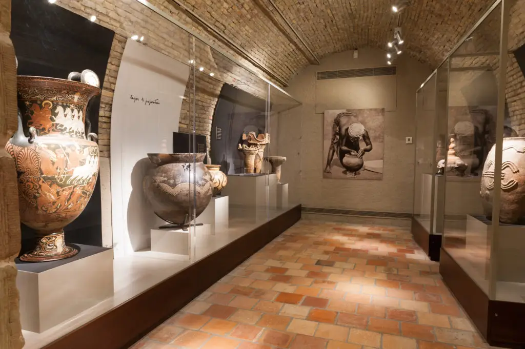 A Greek red-figure volute krater and painted vases in a brick-vaulted gallery