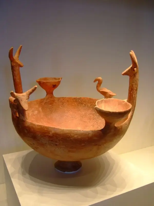 A Cypriot Red Polished ware bowl modelled with cattle, a bird and miniature vessels around the rim