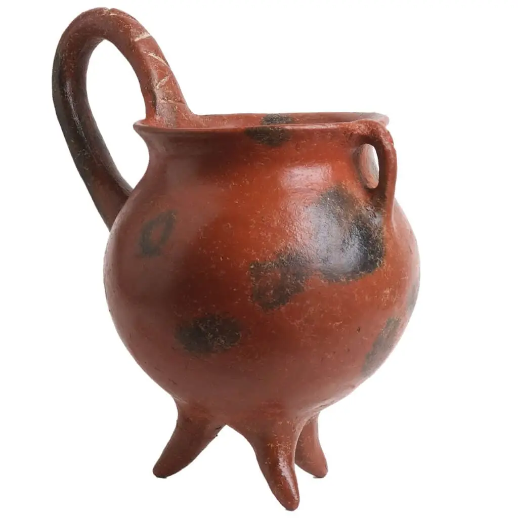 A Cypriot Red Polished ware jug with a globular body on three feet and a high arching handle
