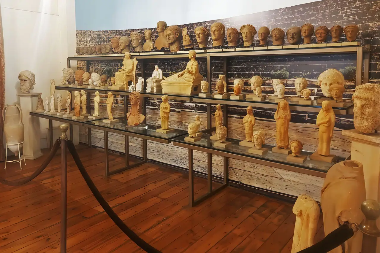 Rows of Cypriot terracotta votive heads and figurines on glass shelves in a museum gallery