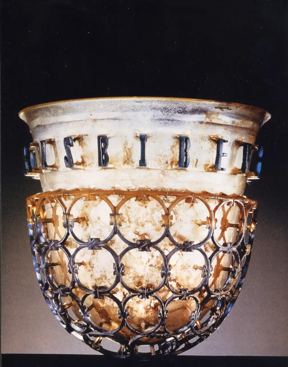 A late-Roman cage cup, an openwork glass shell standing free of the inner beaker on glass struts