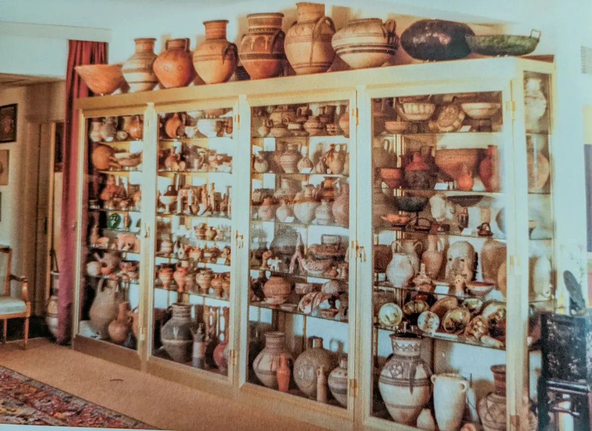 A tall glazed cabinet filled with Cypriot pottery in a domestic interior
