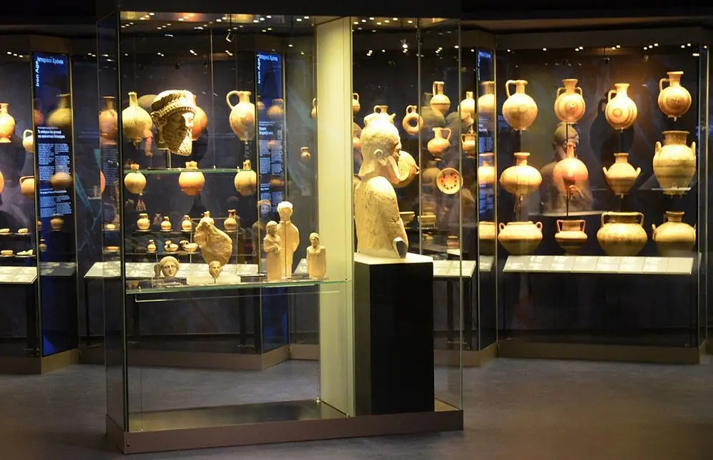 Cypriot painted pottery and limestone figures in lit glass cases in a museum gallery